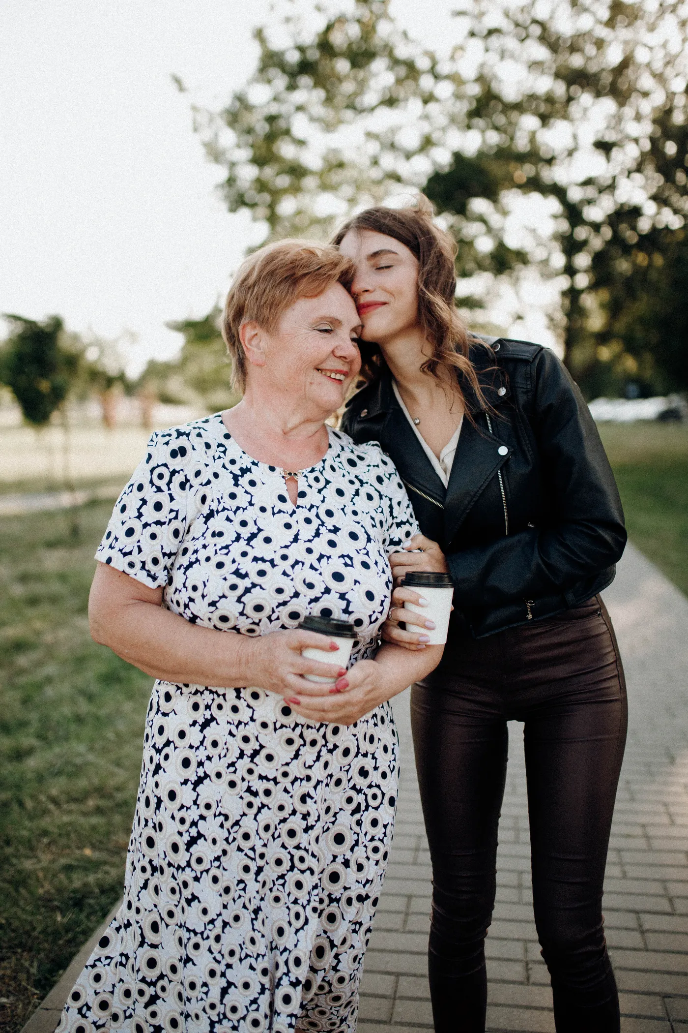 Een jonge vrouw en een oudere vrouw omarmen elkaar tijdens een wandeling